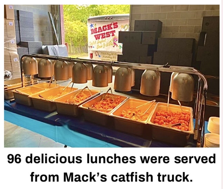 A buffet setup with multiple serving trays containing food, with a sign in the background indicating "Mack's West" and mentioning catfish lunches.
