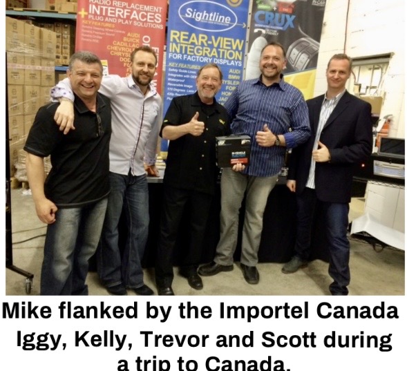 Group photo of six men smiling together at an event, with promotional banners in the background.