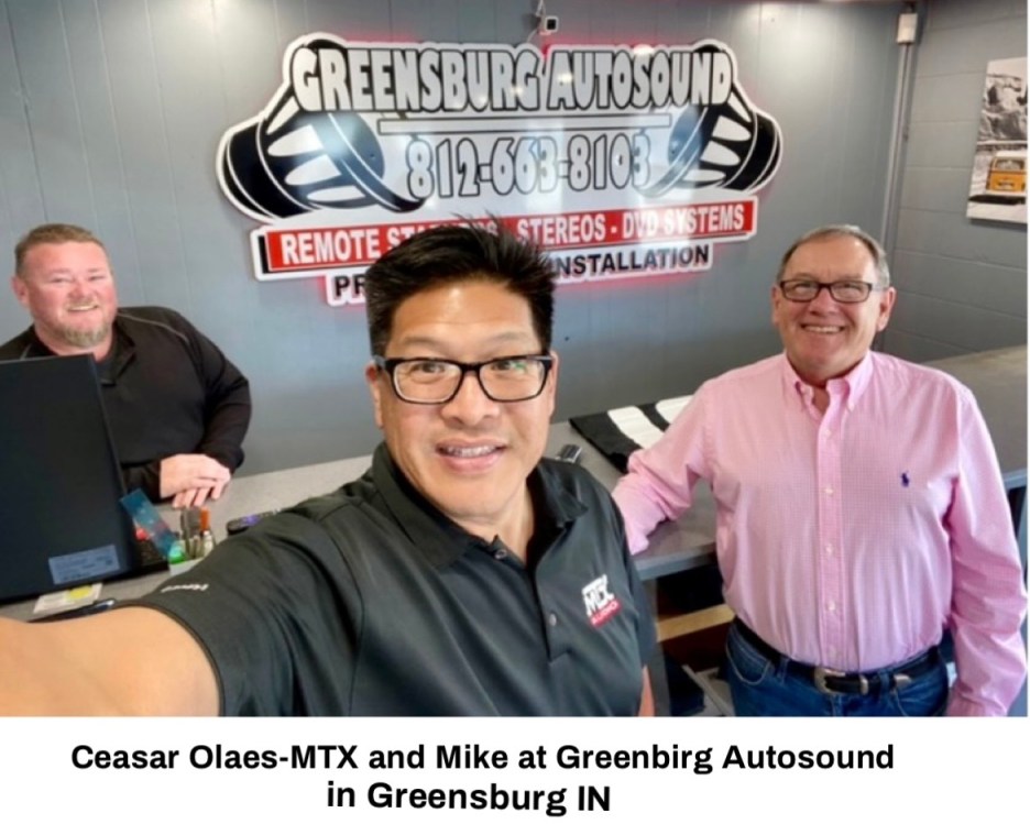 Selfie of Ceasar Olaes-MTX and Mike at Greensburg Autosound, featuring a service area with a sign in the background.