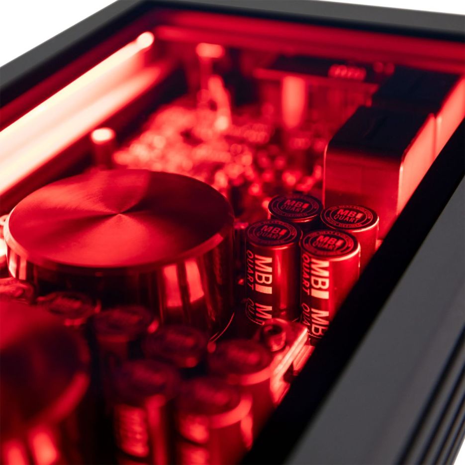 Close-up view of electronic components illuminated with red lighting, featuring cylindrical batteries and a round metallic object.