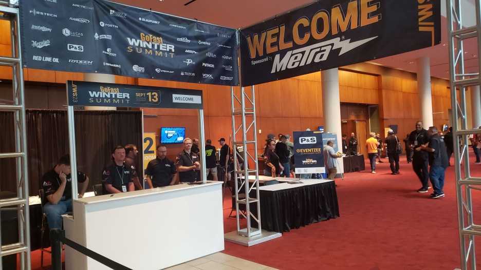 Entry area for the Go Fast Winter Summit featuring a welcome sign, registration desk with staff, and attendees in the background.